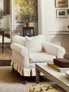 a living room filled with furniture next to a painting on the wall behind a chair