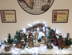 a nativity scene is displayed in the corner of a room with christmas lights on it