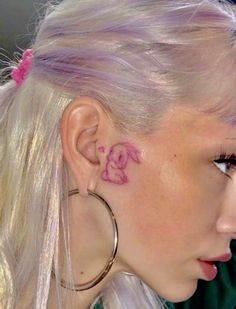 a woman with pink hair has a pig tattoo on her ear