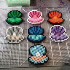 six perlercrafted pieces of different colors and shapes on a table with scissors