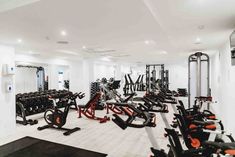 a gym with rows of exercise machines and treadmills on the floor in front of white walls