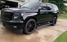 a black suv parked in front of a garage