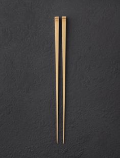 two wooden chopsticks sitting on top of a black surface