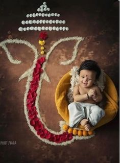 a baby is laying down on a pillow in front of a ganeshi decoration