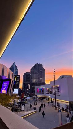 the city skyline is lit up at night with people walking and sitting in the plaza