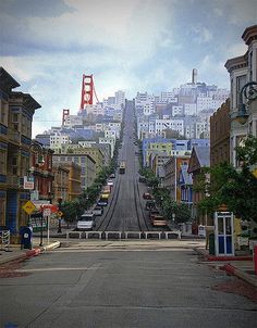 an empty street with cars parked on both sides and the golden gate bridge in the background