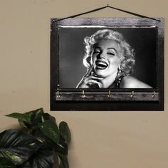 a black and white photo of marilyn monroe hanging on a wall next to a potted plant