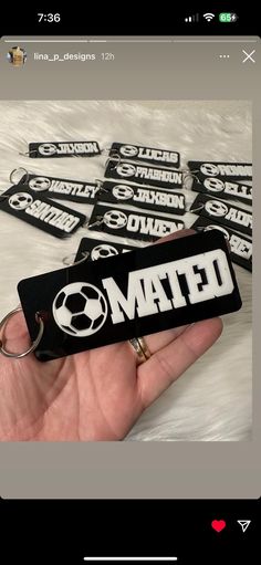 a hand holding a black and white keychain with the word mate on it