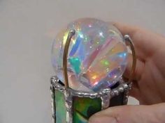 a hand holding a ring with an iridescent stone in it