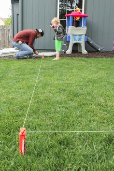 two children are playing in the yard with an orange toy and another child is holding a camera