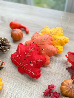 several small stuffed animals sitting on top of a table next to leaves and pine cones