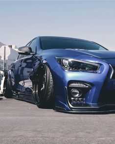 the front end of a blue car parked in a parking lot next to a building