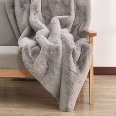 a couch with a blanket on it and a wooden chair in front of the couch