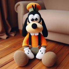 a crocheted dog sitting on top of a wooden floor next to a couch