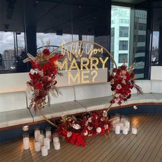 a bench with flowers and candles on it in front of a sign that says will you marry me?