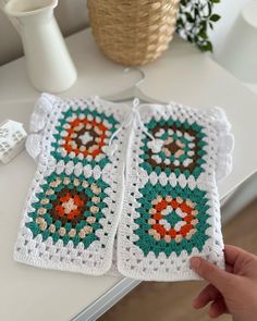 two crocheted coasters sitting on top of a table next to a vase