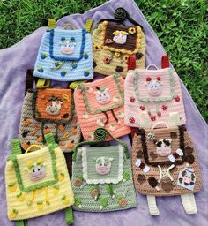 several crocheted purses sitting on top of a purple blanket in the grass