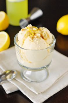 a glass bowl filled with ice cream on top of a table next to lemons