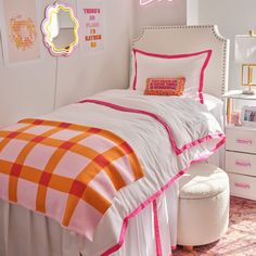 a white bed with pink and orange comforter on top of it in a bedroom