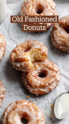 glazed doughnuts with icing on a piece of parchment paper next to a cup of milk