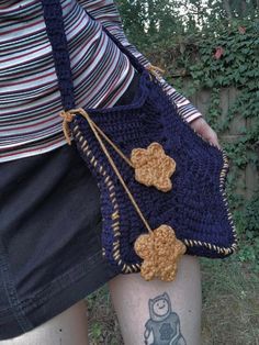 a woman holding a crocheted purse in her left hand and tattoos on her right leg