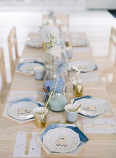 the table is set with blue and white plates, silverware, and vases