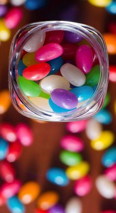 colorful candy beans are in a glass jar