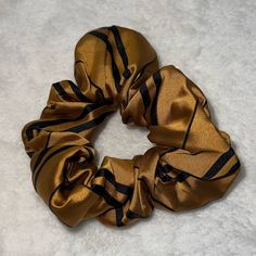 a gold and black hair scrunffle on a white surface with no one around it