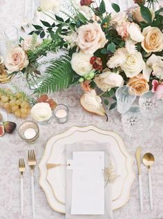 the table is set with white and gold place settings, silverware, and flowers