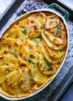 a casserole dish with potatoes and parsley in it on a baking tray