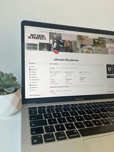 an open laptop computer sitting on top of a white desk next to a potted plant