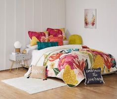 a bed with colorful pillows on top of it and a white rug in the middle