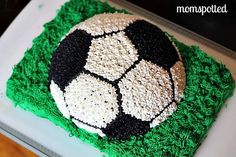 a soccer ball cake with green frosting on a white platter in the shape of grass