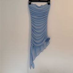 a blue dress hanging on a hanger in front of a white wall with an umbrella