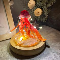 an orange and red jellyfish with lights on it's head sitting on a wooden plate