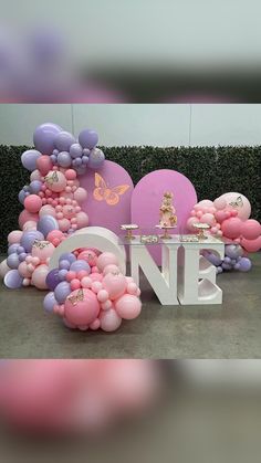 a pink and gold baby shower with balloons on the wall, couches and decorations