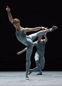 two dancers in blue leotards and white tights, one holding the leg up