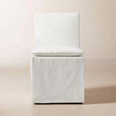 a white chair sitting on top of a floor next to a beige wall in front of it