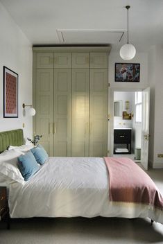 a bed sitting in a bedroom next to a tall wooden cabinet with drawers on each side