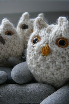 three crocheted owls sitting on top of some rocks with one looking at the camera