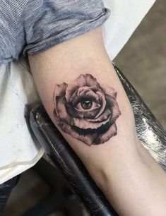 a black and white rose tattoo on the right arm, with an eye in it