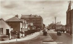 an old black and white photo of a street with cars driving down it's side