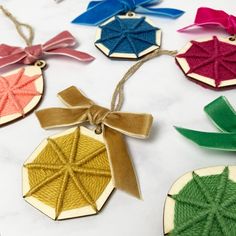 four ornaments with bows on them sitting on a white table top, one in the shape of an ornament