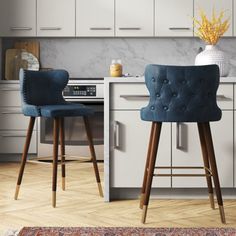 two blue bar stools sitting in front of a kitchen counter with an area rug