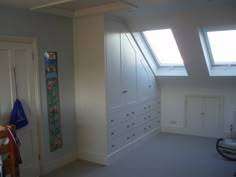 an empty room with white cabinets and skylights