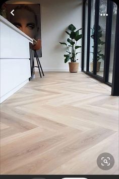 an empty room with wood flooring and plants in the corner, next to a large window