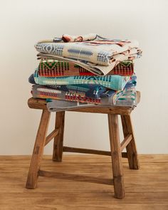 a stack of blankets sitting on top of a wooden stool