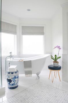 a white bathtub sitting next to a window in a bathroom with blue and white decor