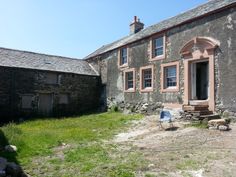 an old stone house with a chair in the yard