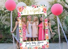 a group of women standing next to each other in front of a sign that says it's a girl